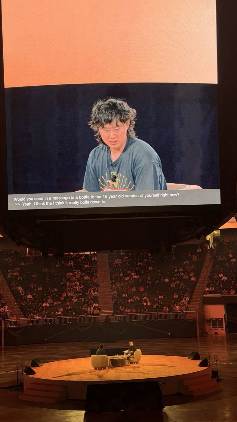 Jumbotron caption asking for a message in a bottle to an 18 year old self, the full arena below